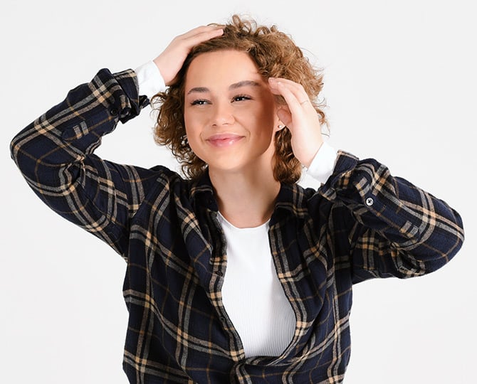 Glueckliche Frau laechelt und greift sich in die Haare