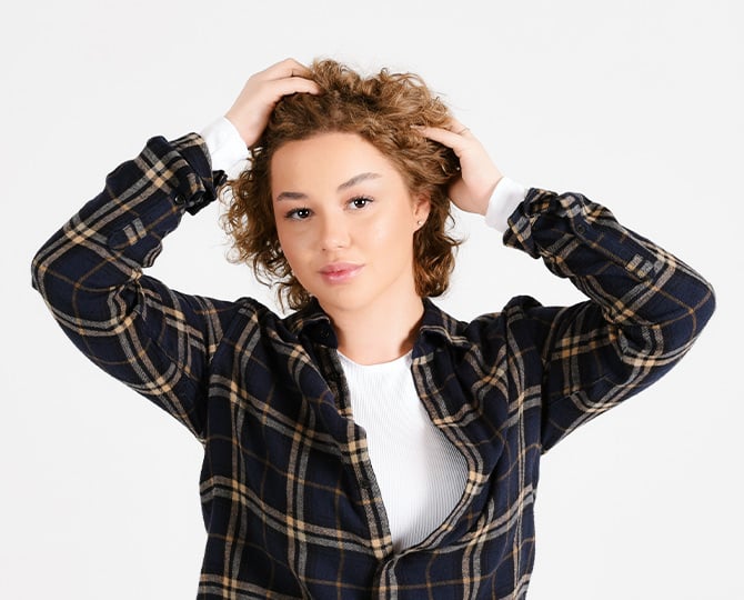 Frau greift sich in die Haare und laechelt dabei